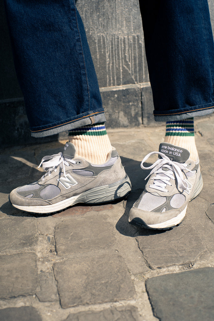 A pair of socks with stripes in ecru, green, and blue colors, with the brand name ' Escuyer ' visible on the foot area.