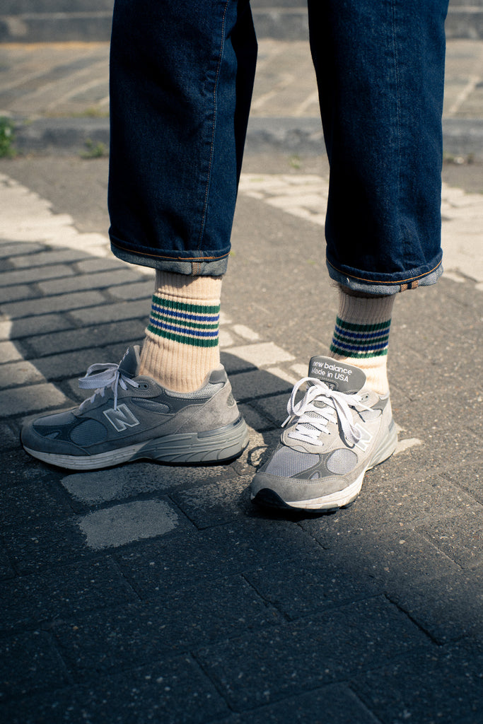 Person wearing striped socks from Escuyer brand with New Balance sneakers