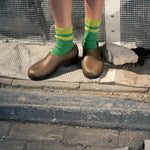 Person wearing green socks with yellow stripes made of wool and cashmere 