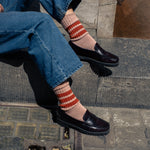Woman wearing off orange and bright orange striped crew socks by Escuyer, made in Portugal