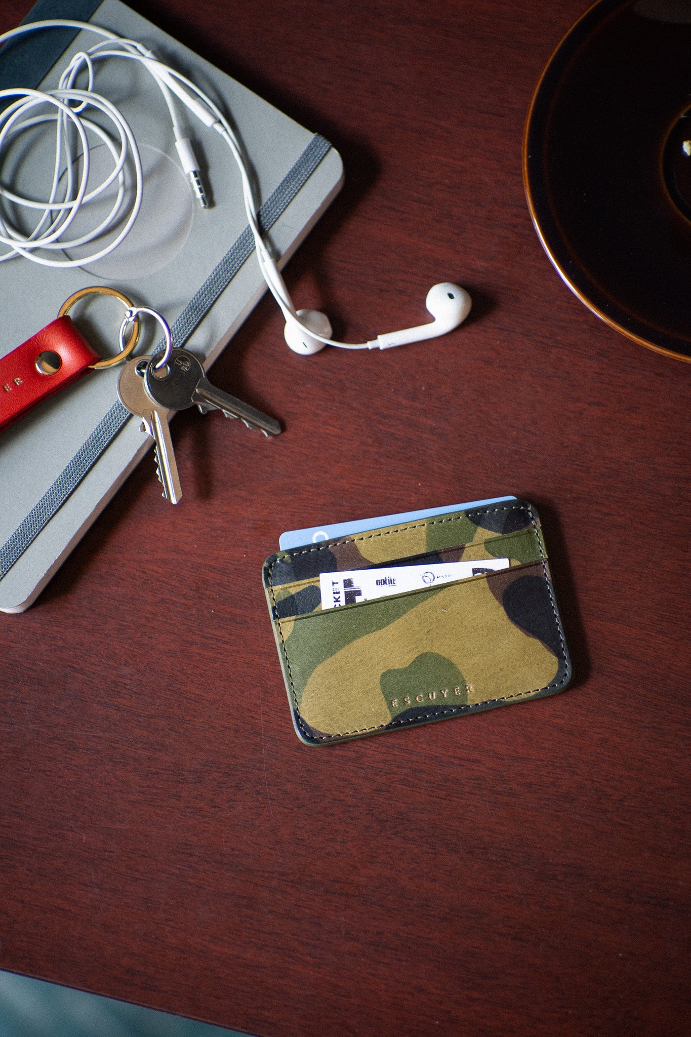 Escuyer camouflage leather cardholder with keys and accessories on wooden surface — lifestyle shot