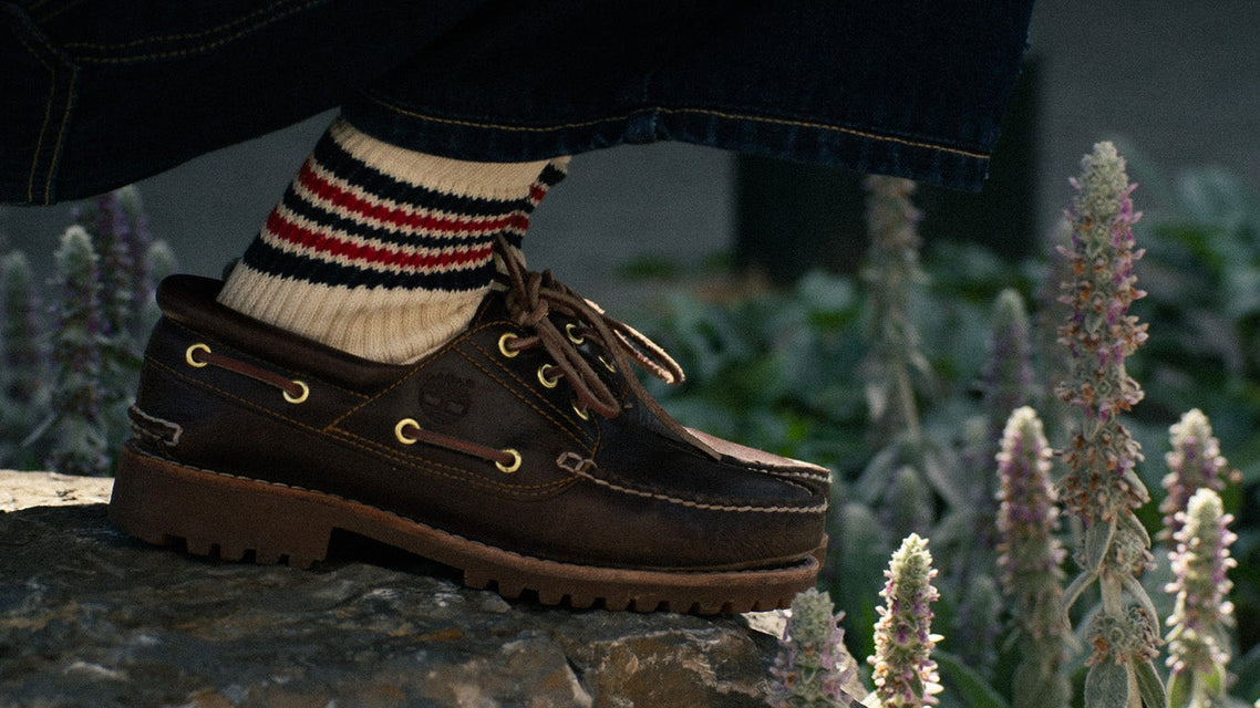 Person wearing brown boat shoes from Timberland and colorful 5 Stripes socks made of cotton and produced in Portugal