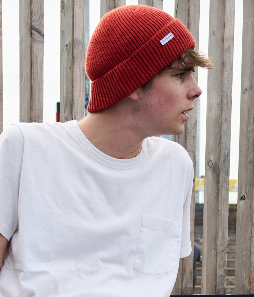 Person wearing an orange ribbed merino wool beanie by Escuyer