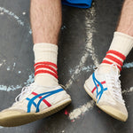 Man wearing ecru and orange striped crew socks by Escuyer, made in Portugal