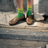 Person wearing green socks with yellow stripes made of wool and cashmere 